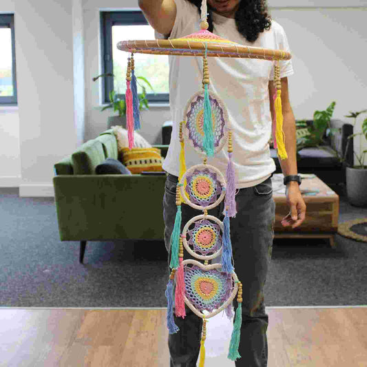 Person holding a Large Drama Dreamcatcher - Pastel Rainbow in a living room setting