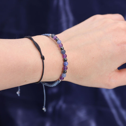 Close-up of a wrist wearing a gemstone bracelet against a dark background