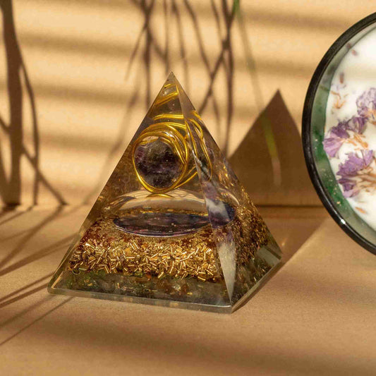 Pyramid-shaped crystal with gold elements on a beige surface