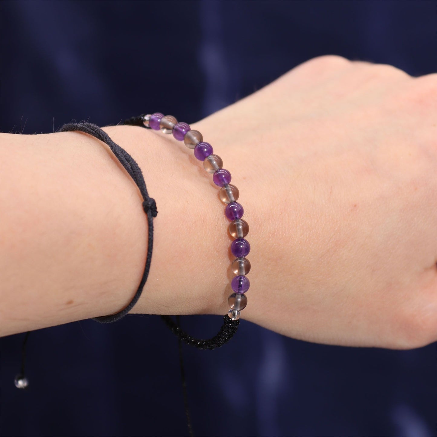 Gemstone bracelet on a wrist against a dark background