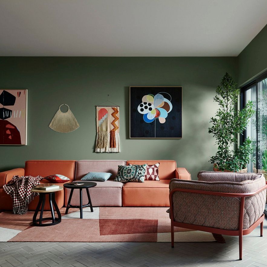 Modern living room with a pink sectional sofa, abstract art on the wall, and a patterned rug.