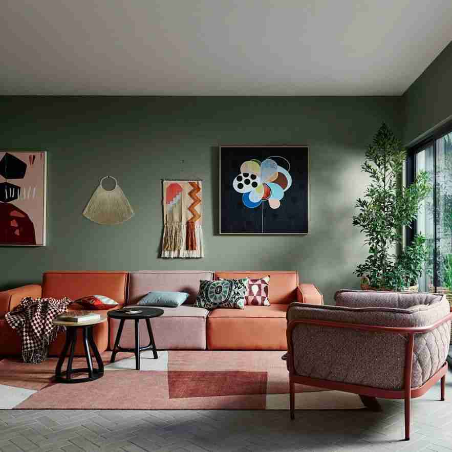 Modern living room with a pink sectional sofa, abstract art on the wall, and a patterned rug.
