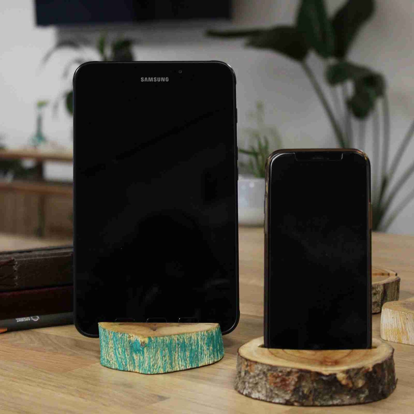 Two smartphones on wooden stands with a blurred indoor background