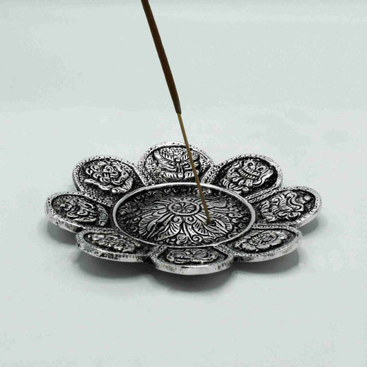Decorative silver incense holder with a single incense stick on a light gray background