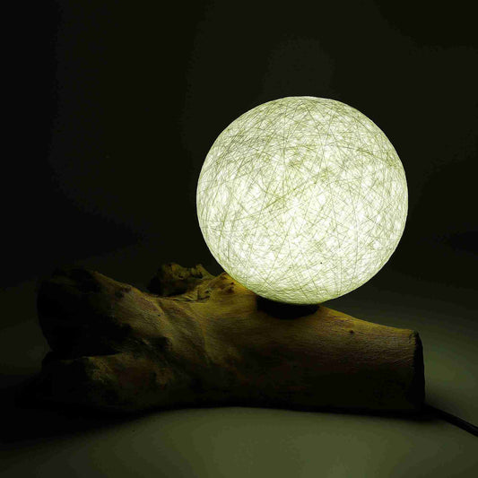 Spherical light bulb on a wooden log against a dark background