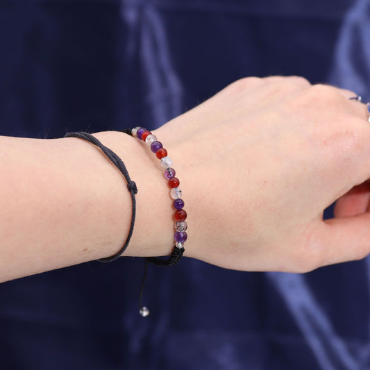 Close-up of a wrist wearing a gemstone bracelet with a dark background