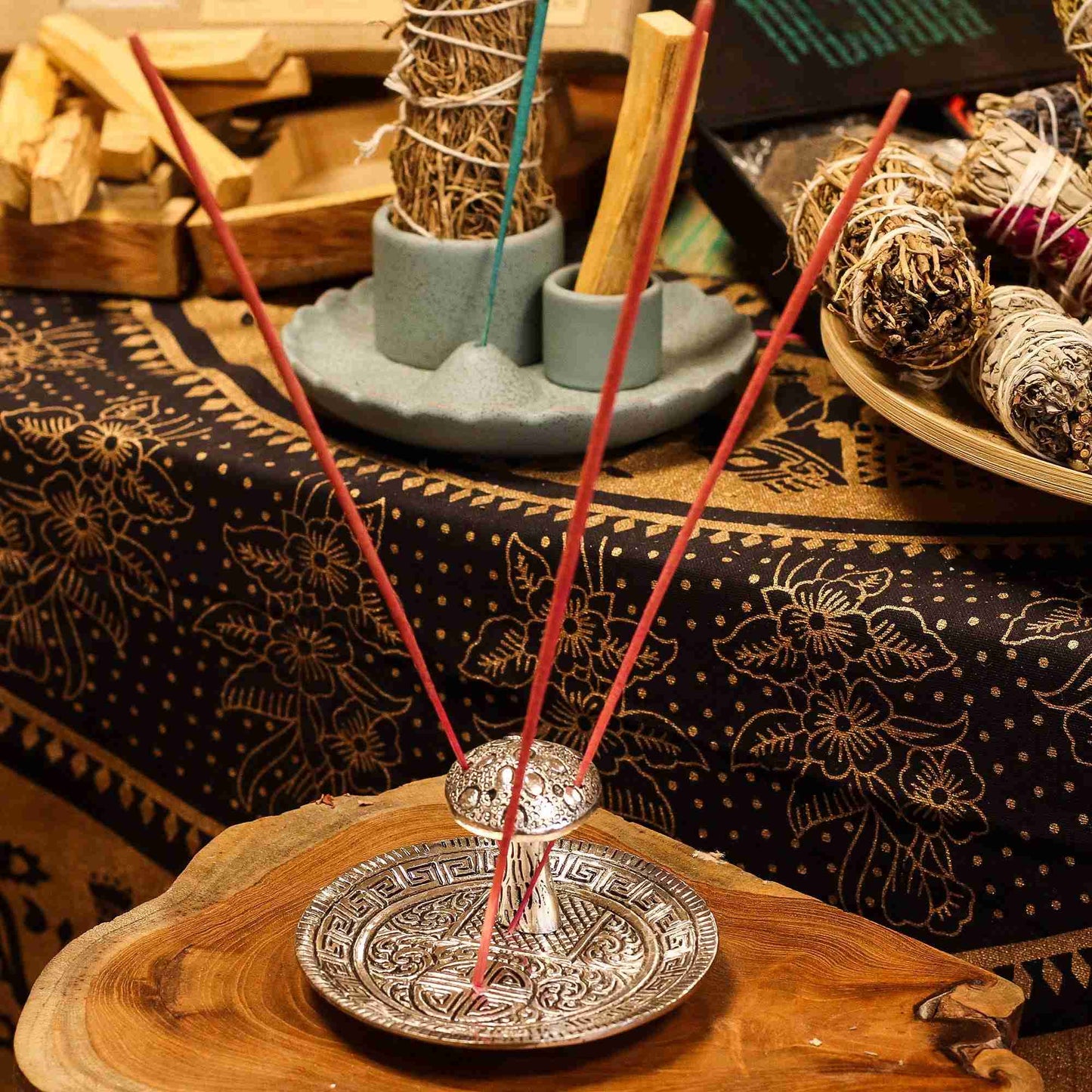 Incense sticks in a holder on a wooden surface with a patterned cloth in the background