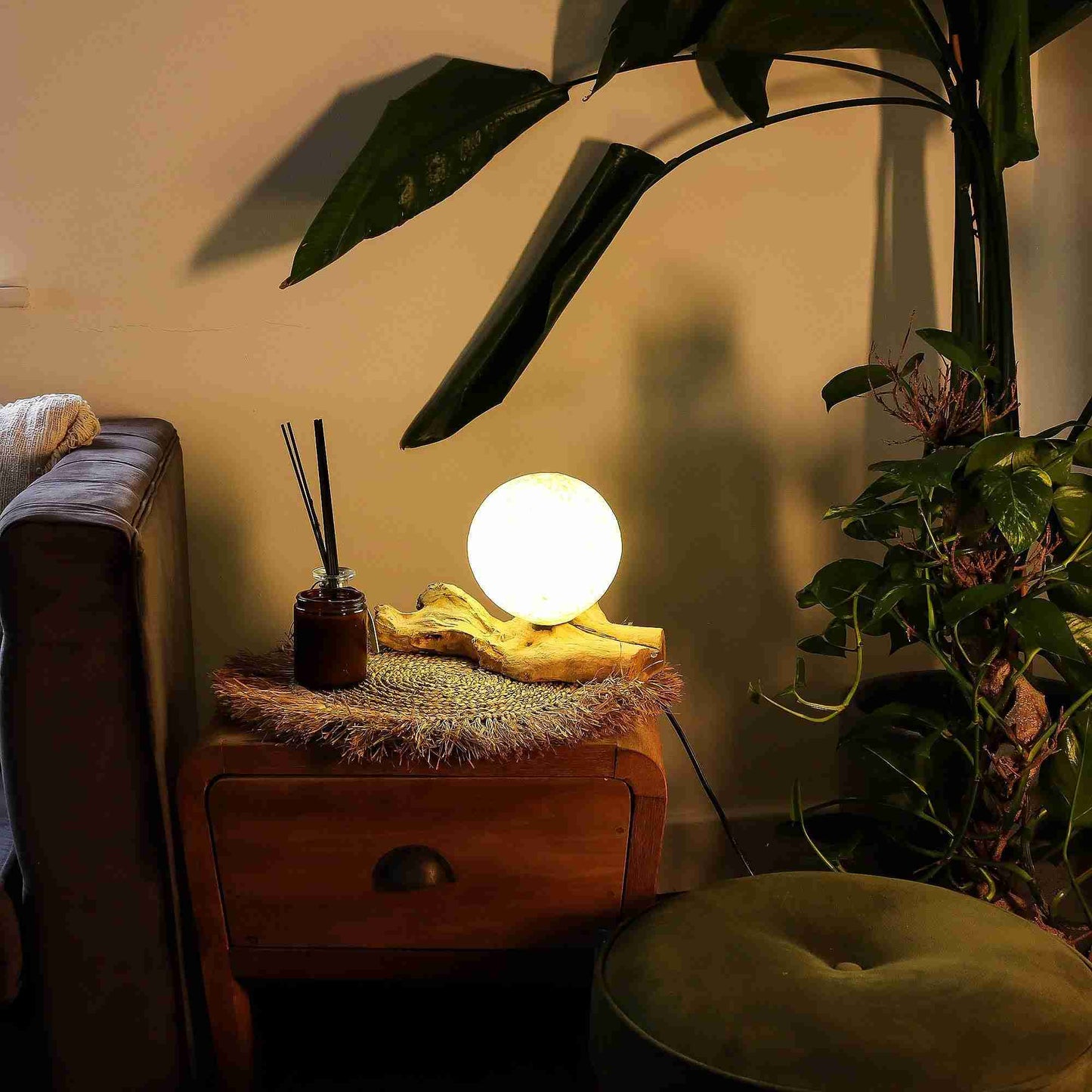Nestled corner with a wooden side table, glowing lamp, and plants