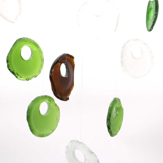 Colourful circular glass bottoms hanging against a white background
