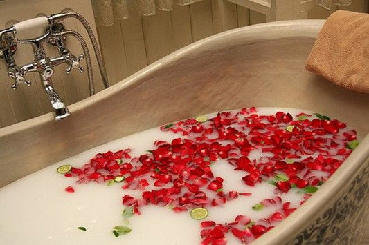 Red soap flower petals dissolving in bath water creating luxurious spa experience