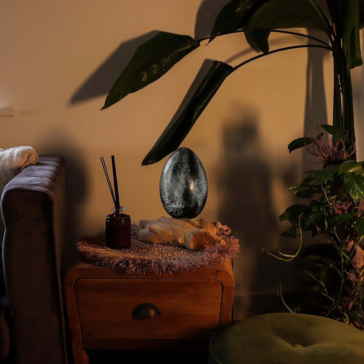 Decorative object on a wooden surface with plants and a sofa in the background