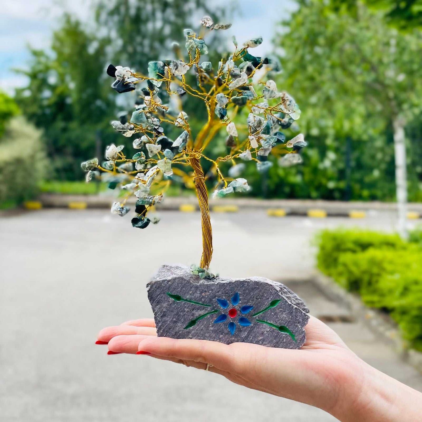 Hand holding a Indian Gemstone Tree - Moss Agate (160 Stones), outdoors.