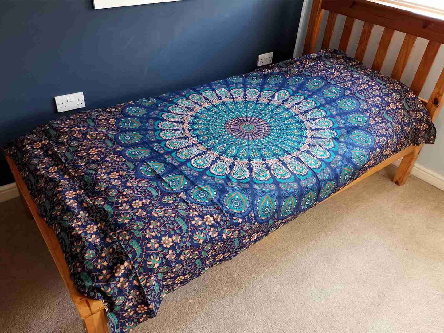 Bed with a Single Cotton Bedspread / Wall Hanging - Classic Mandala in a room with blue walls and beige carpet.