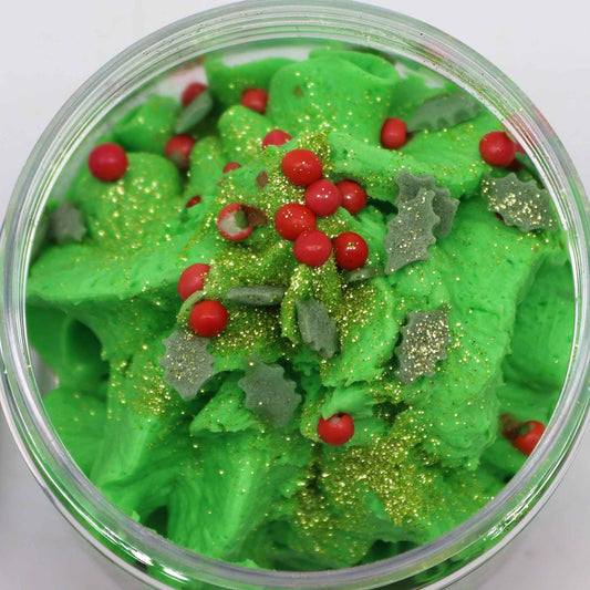 Green whipped soap with red berries and gold glitter in a clear container.