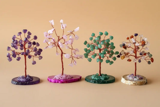 four beautiful gemstone trees, amethyst (purple), rose quartz (pink), green aventurine (green), and multi-stone (rainbow) arranged together in an elegant, premium composition