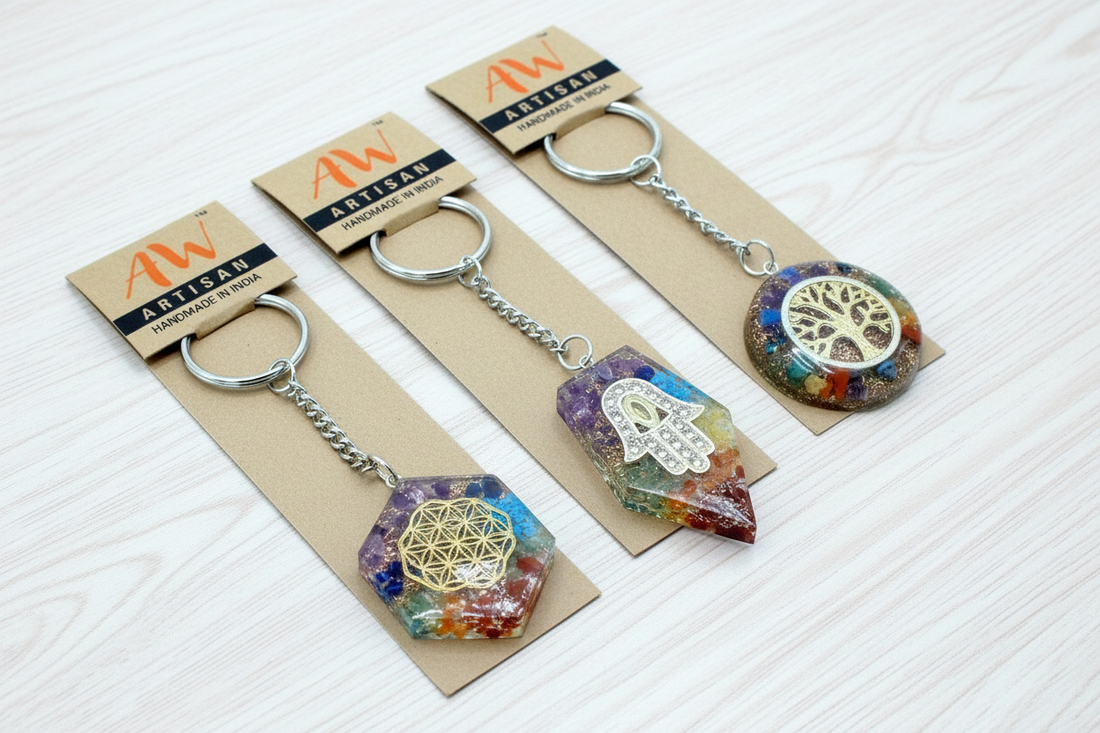 Collection of handcrafted orgonite keyrings in various shapes including round seven chakra, octagon flower of life, hamsa hand, rose quartz hearts, and tree of life designs with embedded gemstones and resin