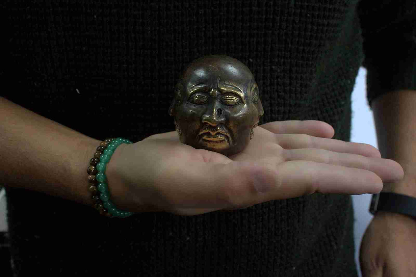 Brass Feng Shui Four-Faced Buddha Figurine held in a hand.