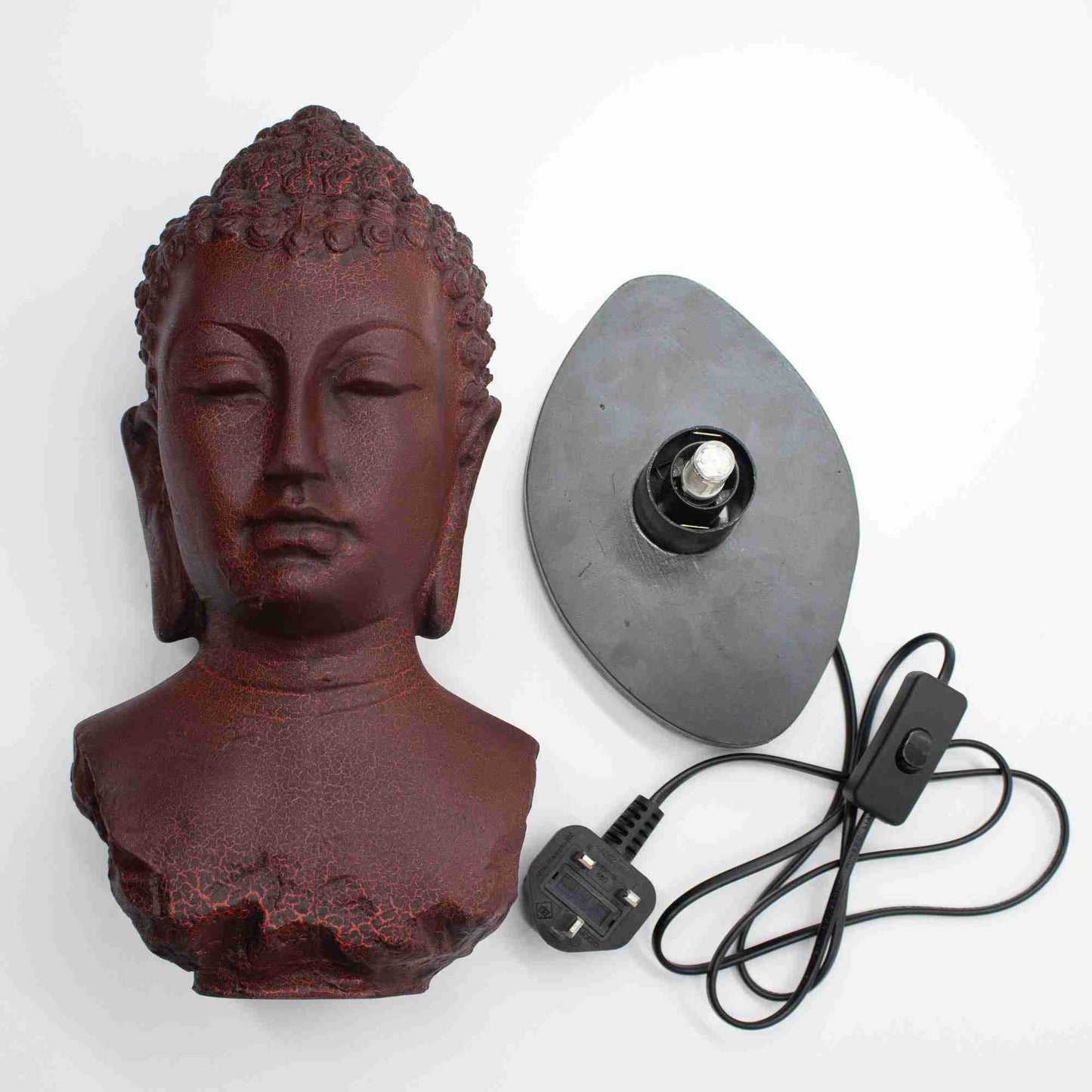 Buddha head sculpture with a lamp base and power cord on a white background