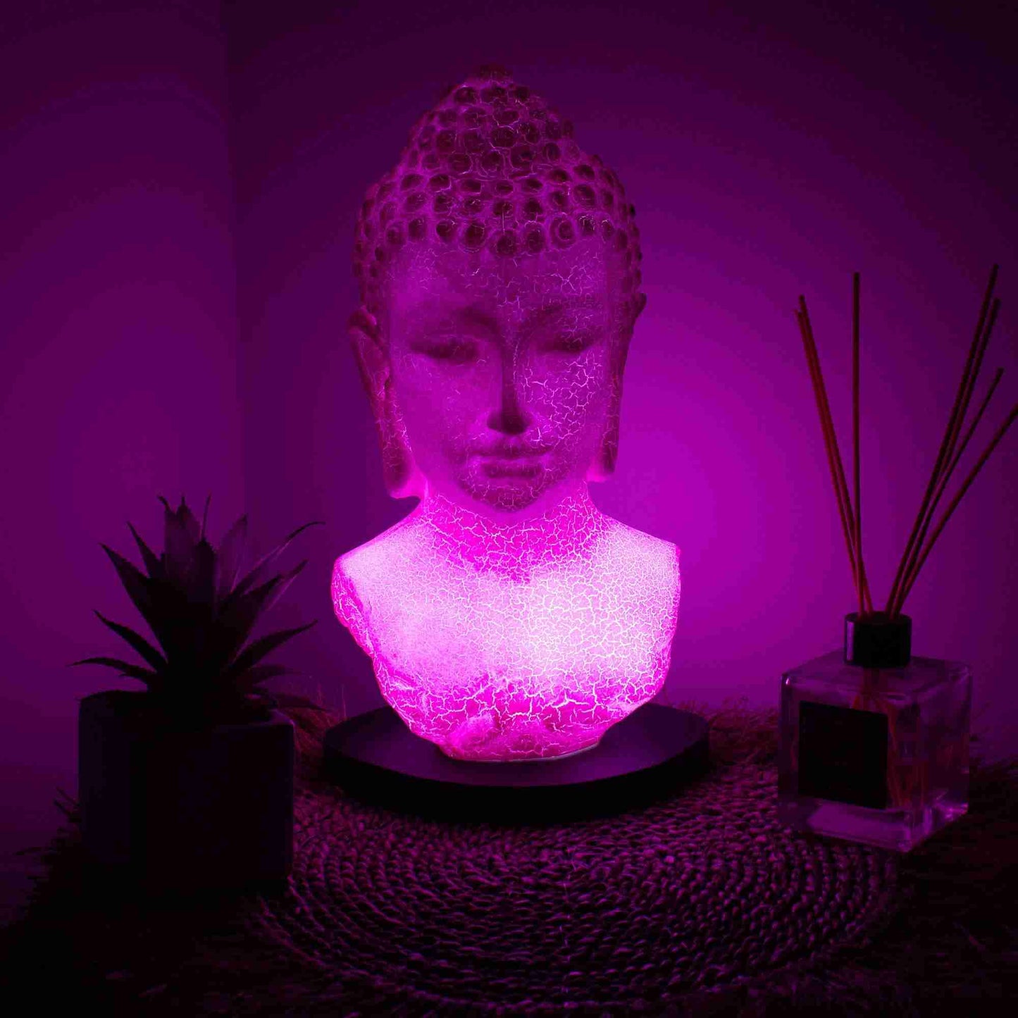 Cherry Crackle Buddha Bust Lamp with a pink glow on a dark surface.