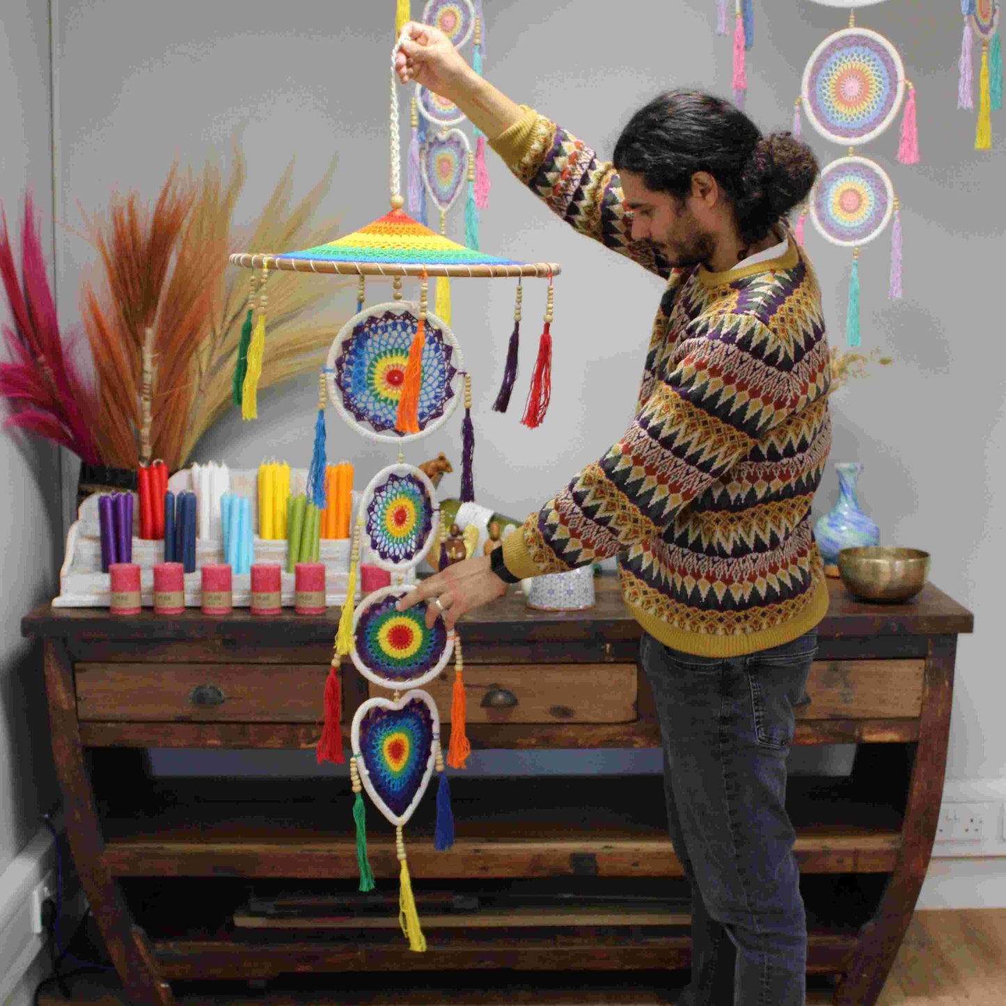 Person arranging Extra Large Drama Dreamcatcher Vivid Rainbow in a room with decorative items.