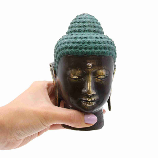 Large Antique Brass Buddha Head Figurine held by a hand with a white background.