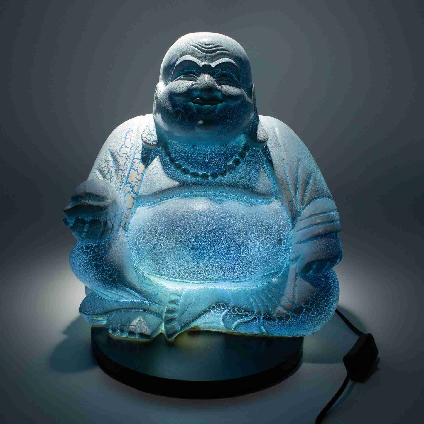 Laughing Buddha Lamp, Sky Blue with a glowing light on a dark background