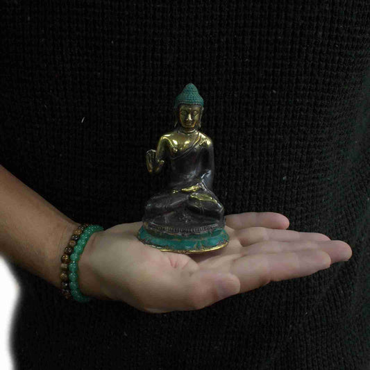 Medium Brass Buddha Figurine Hand Up Sitting held in a hand against a black background