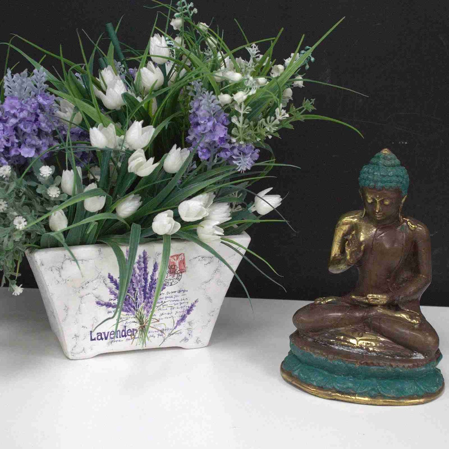 Bouquet of white tulips and lavender with a Medium Brass Buddha Figurine, Hand Up, Sitting on a white surface.