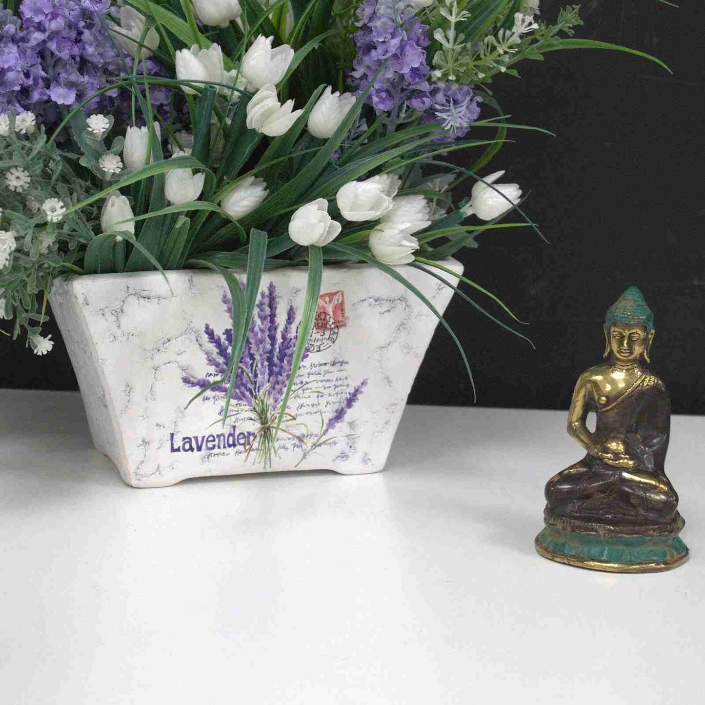 Decorative planter with lavender and tulips next to a Mini Brass Buddha Figurine, Sitting Meditating 