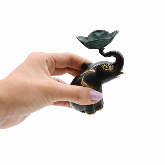 Hand holding a Small Brass Elephant Candle / Incense Holder on a white background.