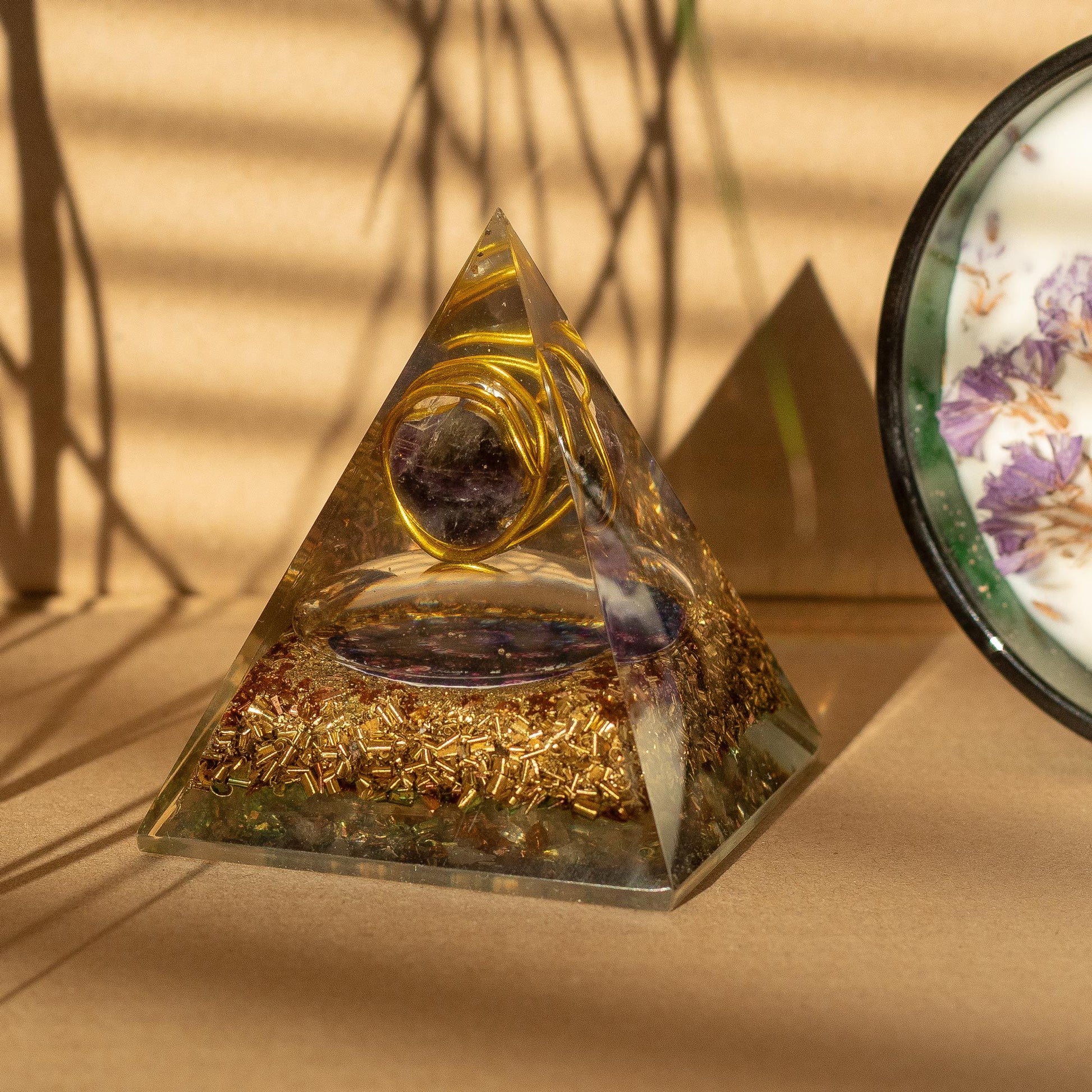 Pyramid-shaped crystal with gold elements on a beige surface