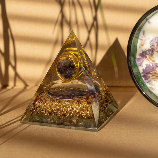 Pyramid-shaped crystal with gold elements on a beige surface