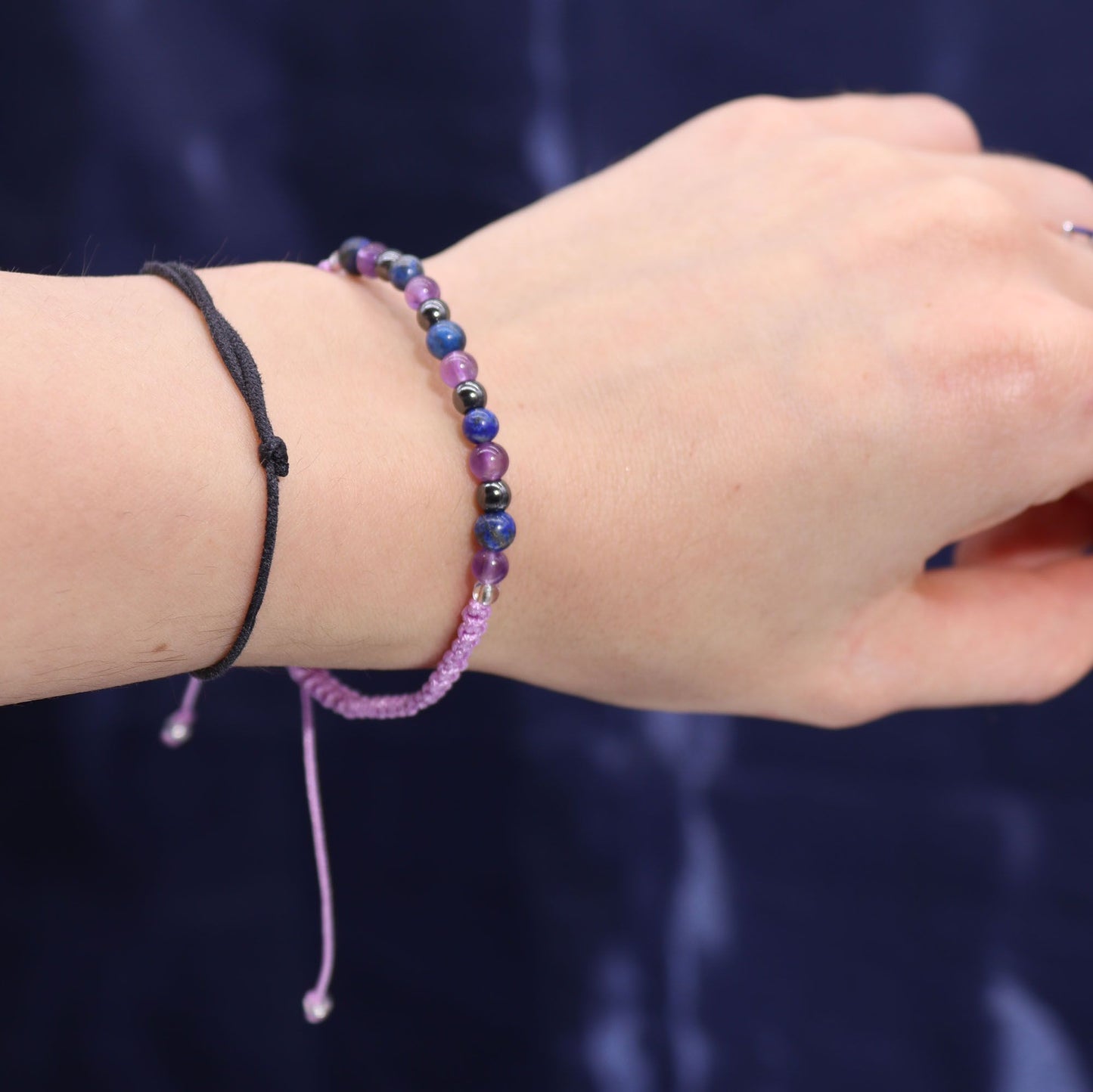 Close-up of a wrist wearing a gemstone bracelet against a dark background 