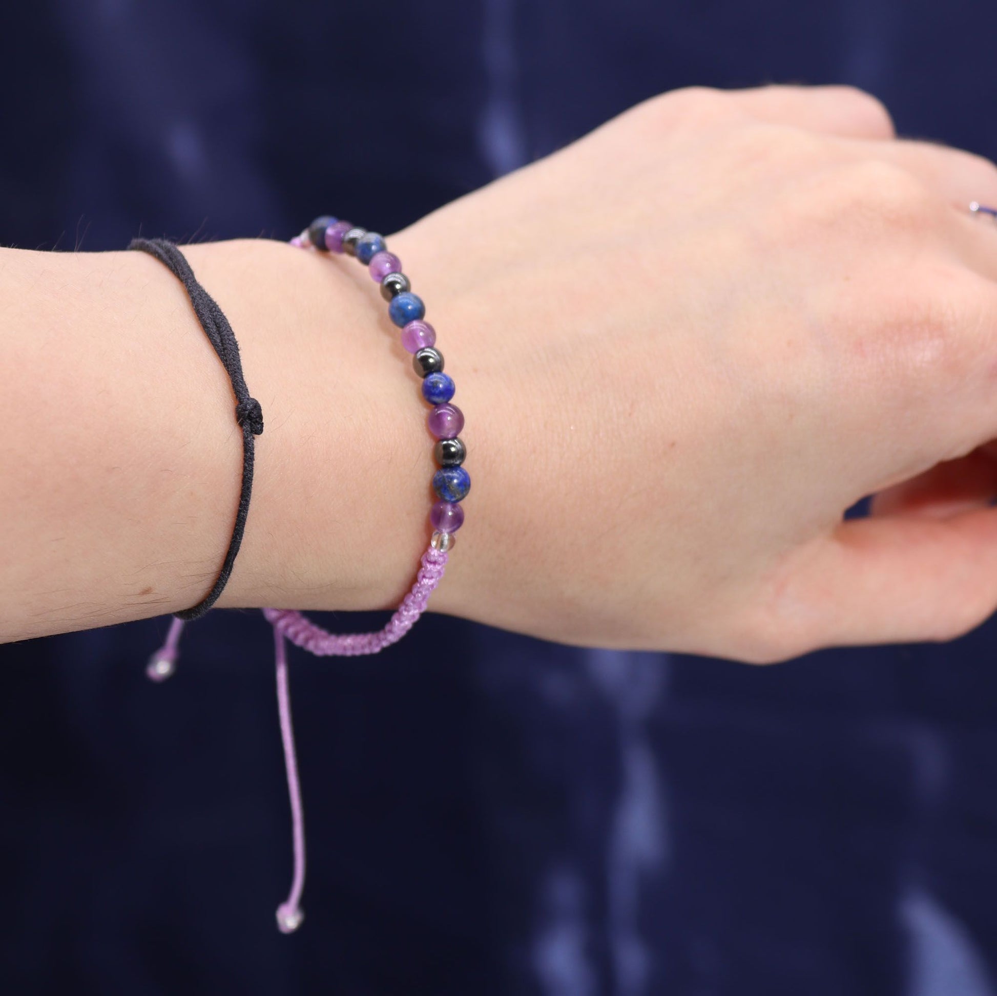 Close-up of a wrist wearing a gemstone bracelet against a dark background 