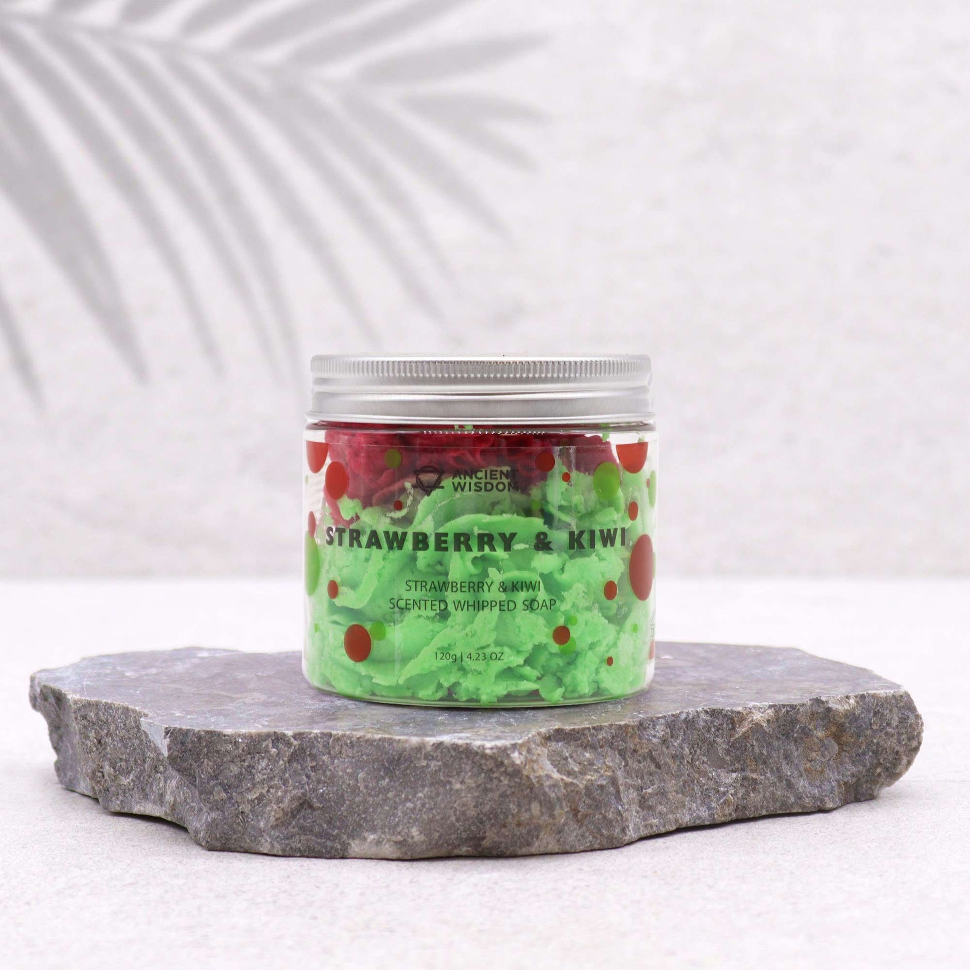 Jar of strawberry and kiwi scented whipped soap on a stone platform with a white background
