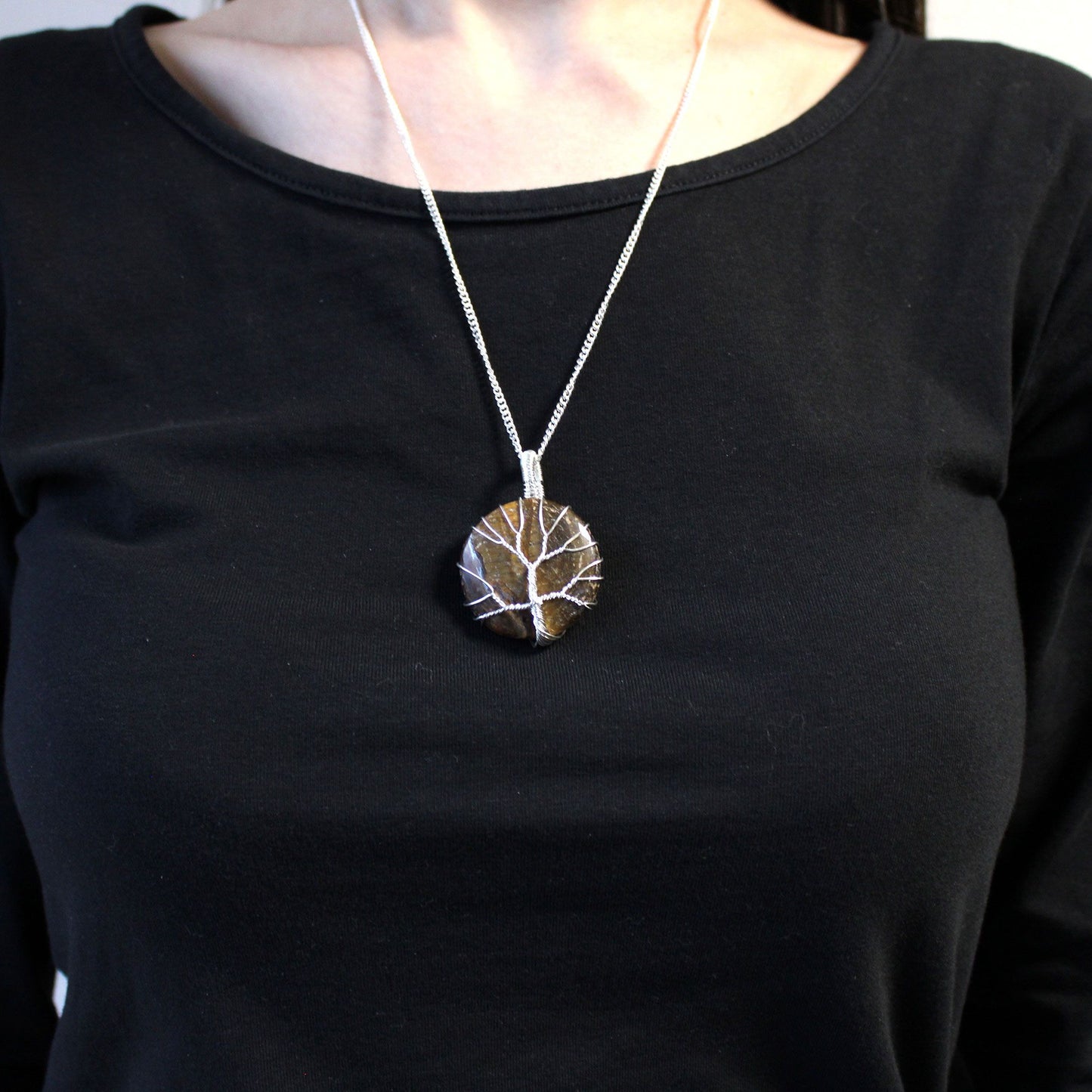 Person wearing a black shirt with Tree of Life Gemstone Necklace - Tiger Eye