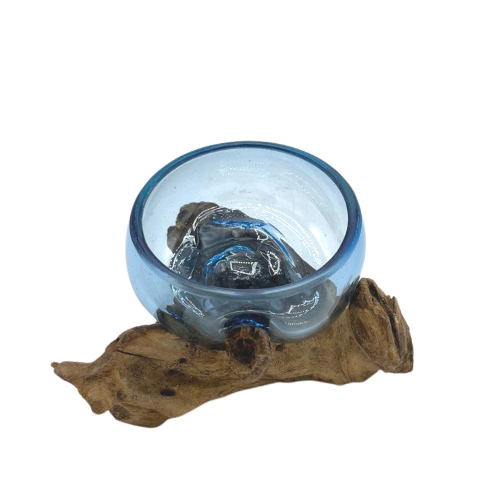 Blue molten glass bowl on a piece of gamal wood against a white background