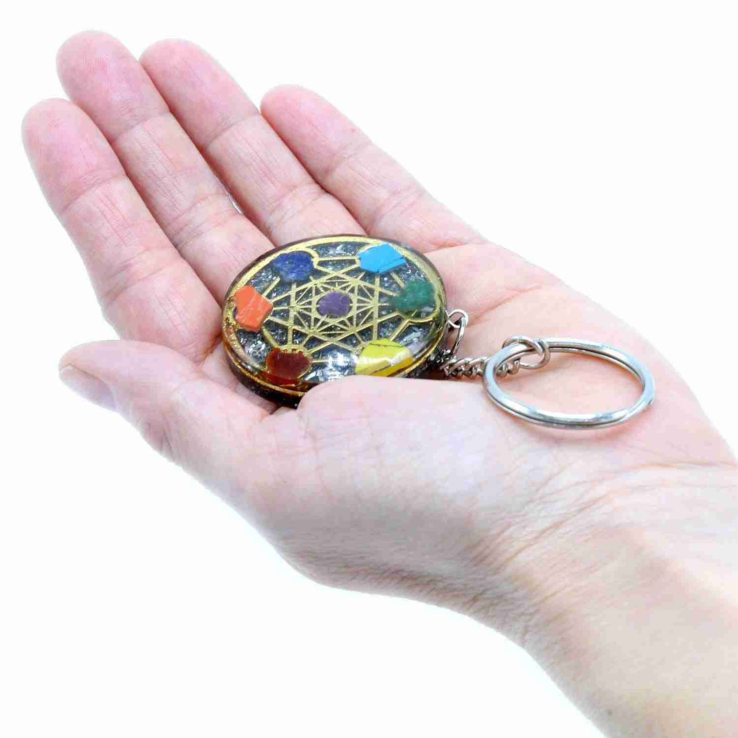 Orgonite Power Keyring - Round Seven Chakra held in a hand against a white background