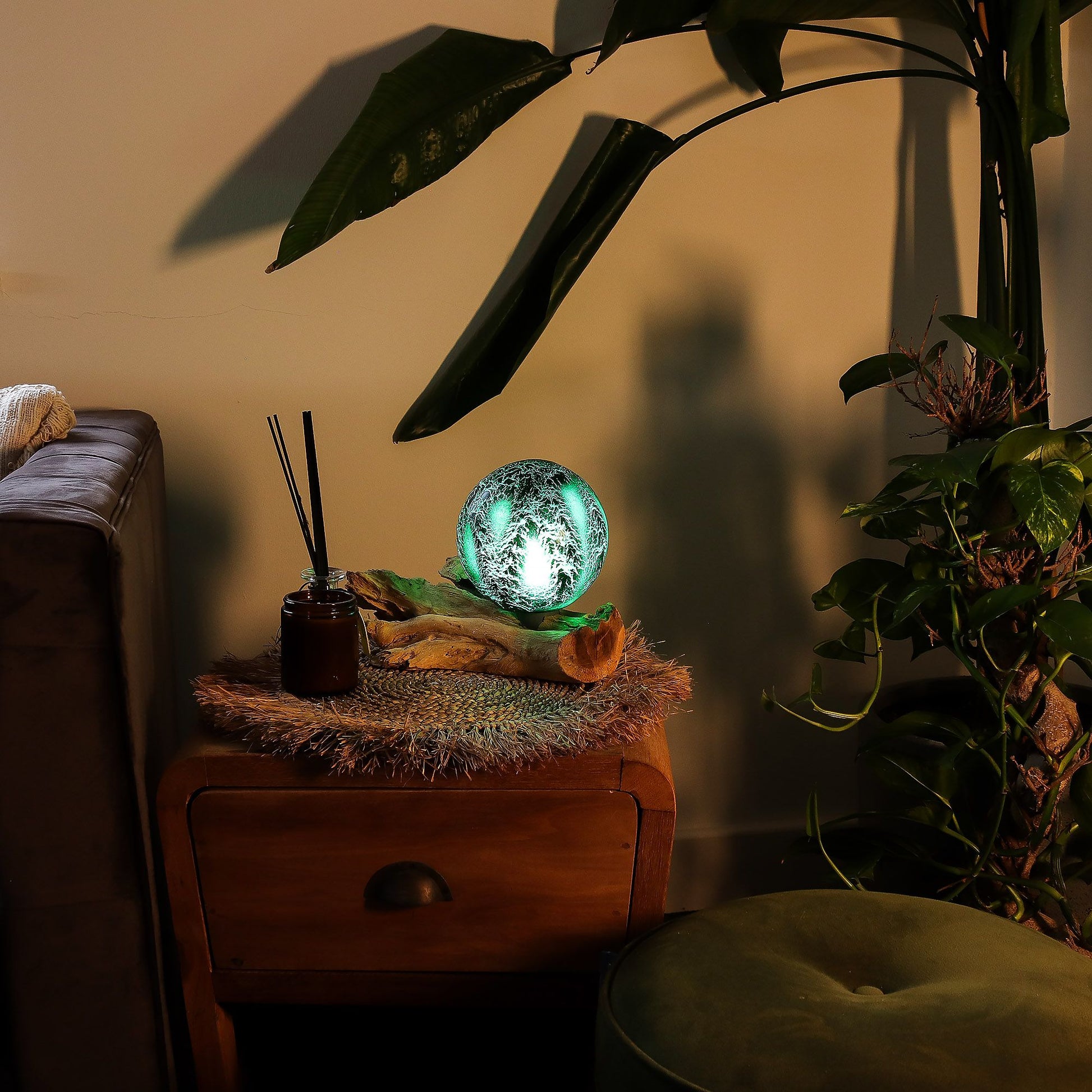 Decorative lamp on a wooden side table with plants and a couch in the background