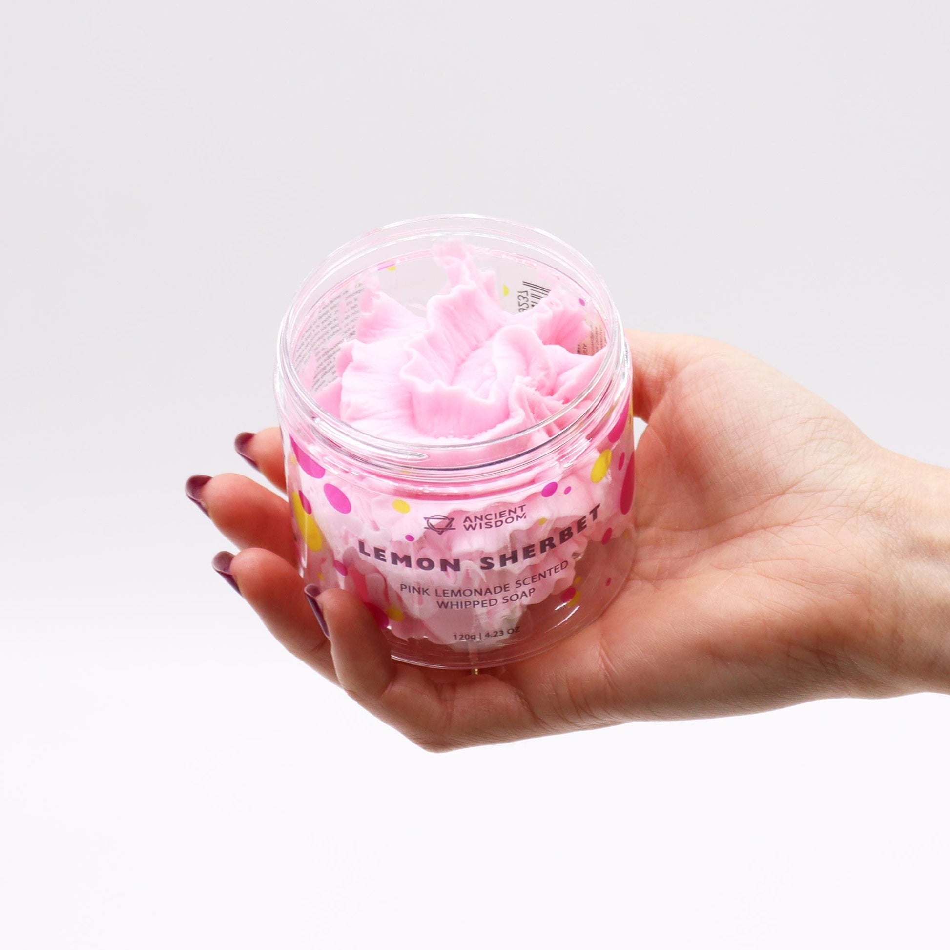 Hand holding a container of pink lemon sherbet soap with visible brand name.