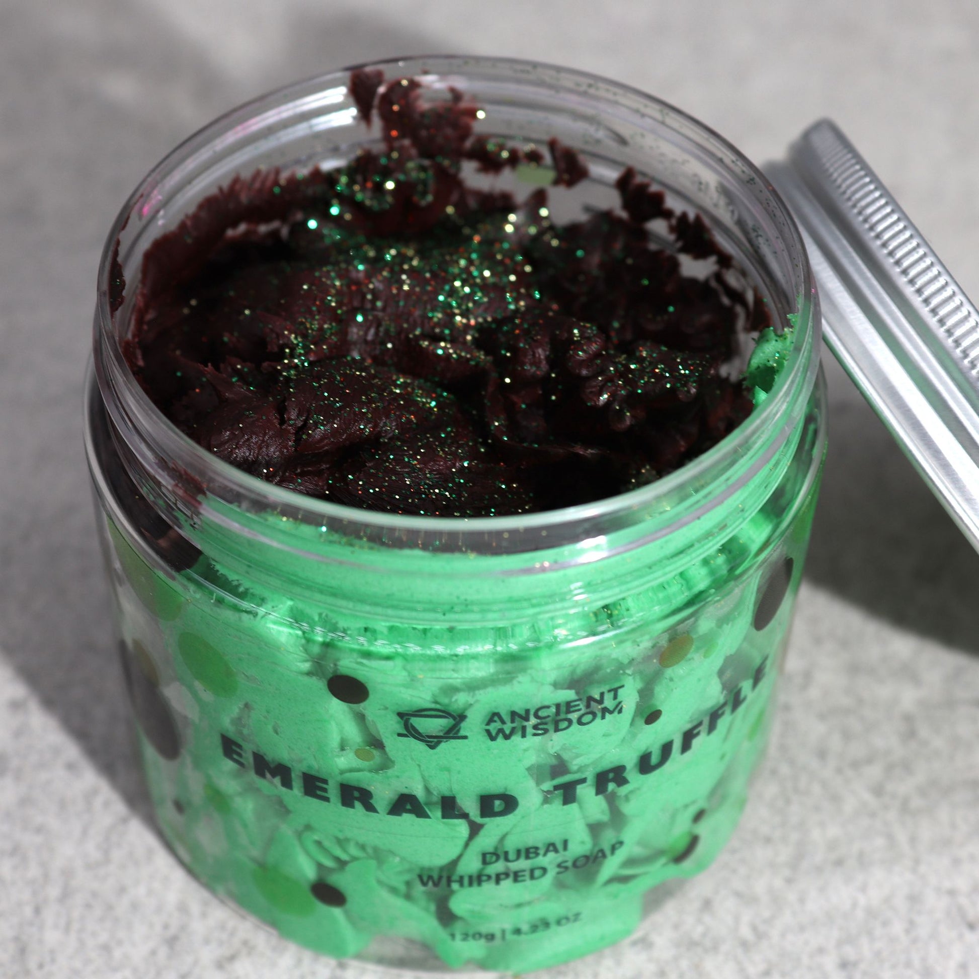 Jar of Emerald Truffle whipped soap with green and black design on a gray background