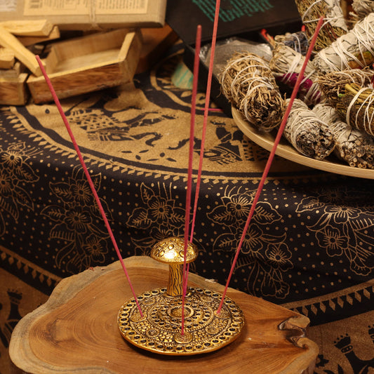 Incense stick holder with incense sticks on a wooden surface with smudge pots in the background.