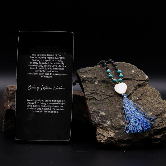 Essence of Volcano Necklace with blue tassel on a dark stone surface with descriptive text card
