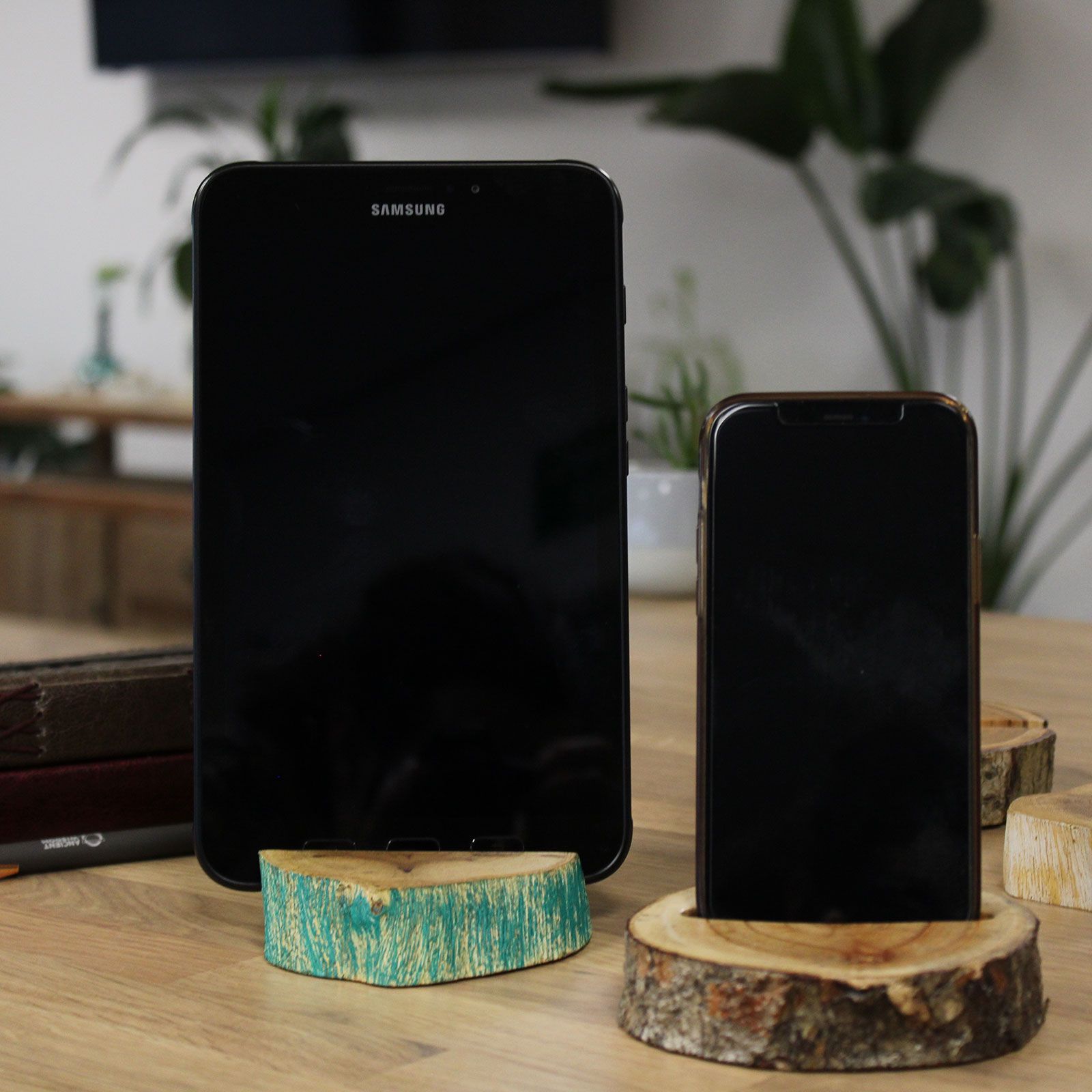Two smartphones on wooden stands with a blurred indoor background