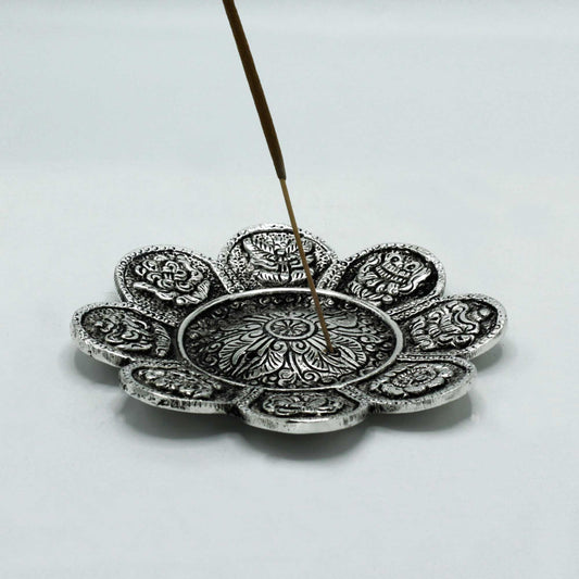 Decorative silver incense holder with a single incense stick on a light gray background