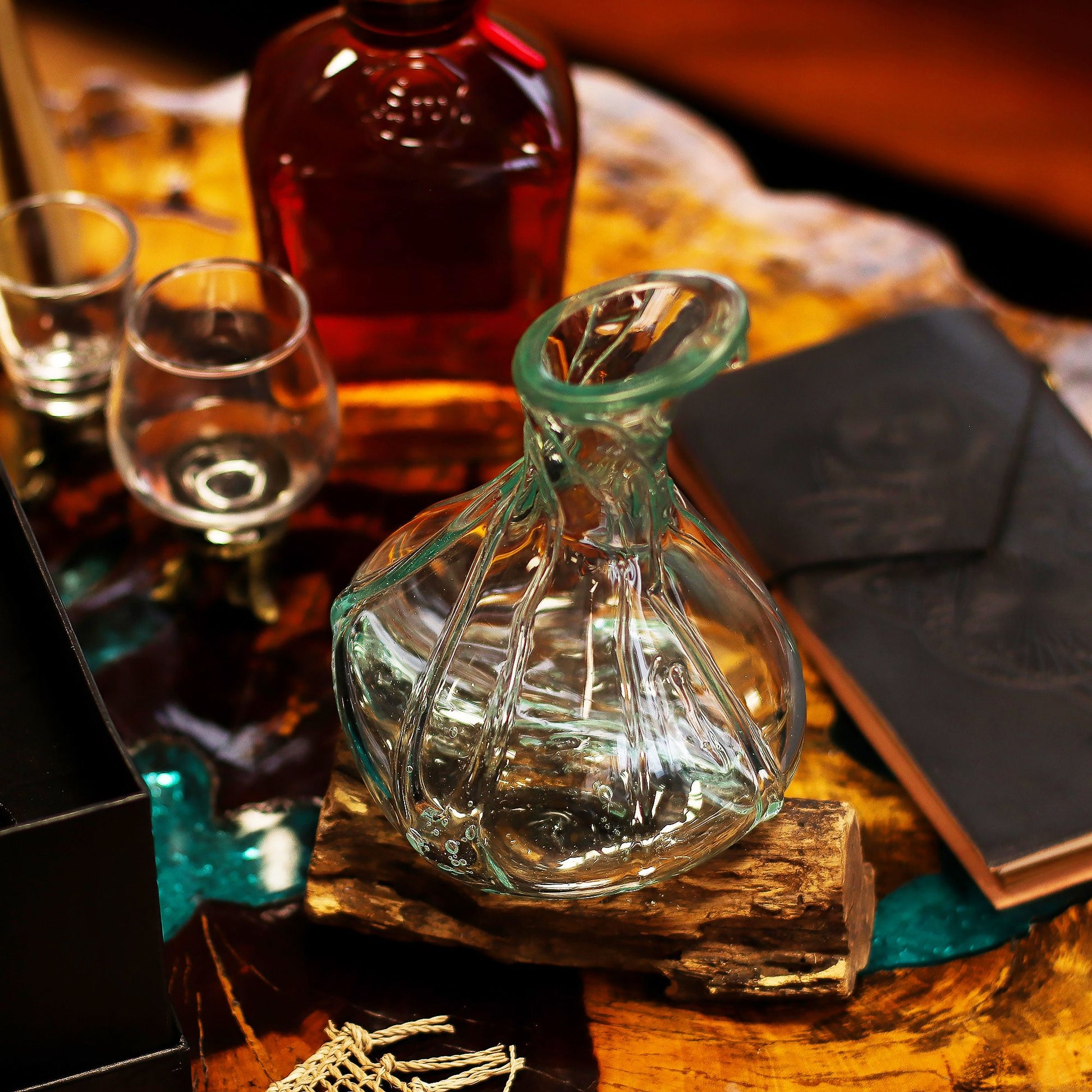 Glass decanter, bottle, and glasses on a wooden surface with a wallet.