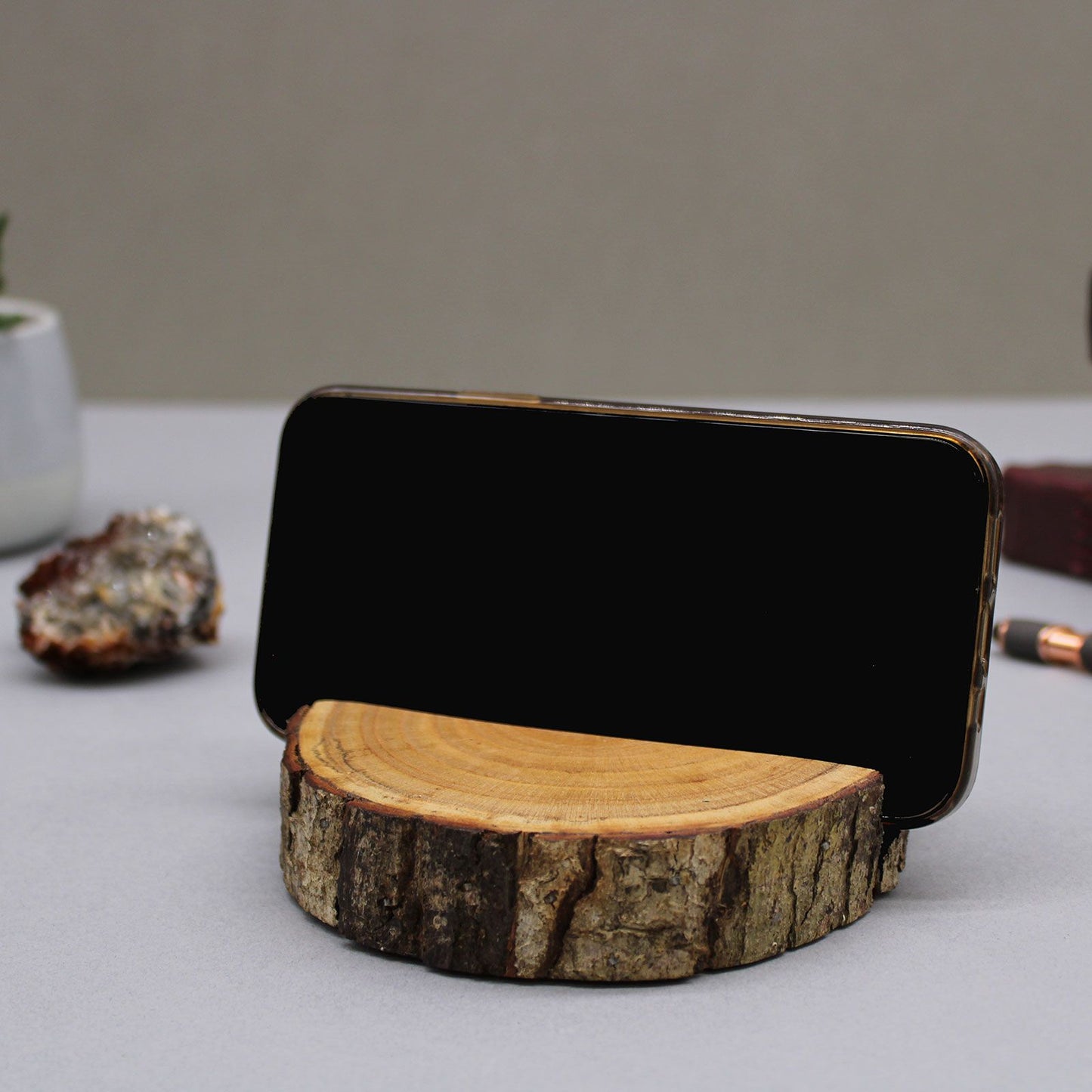 Phone stand made from a wooden log on a neutral background