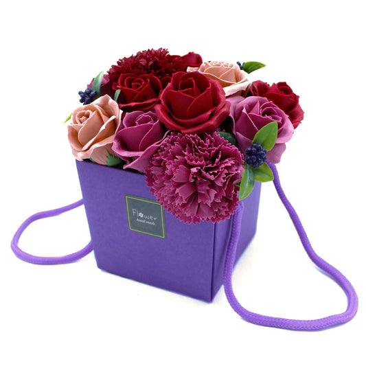 Floral soap flower arrangement in a purple gift box with a strap