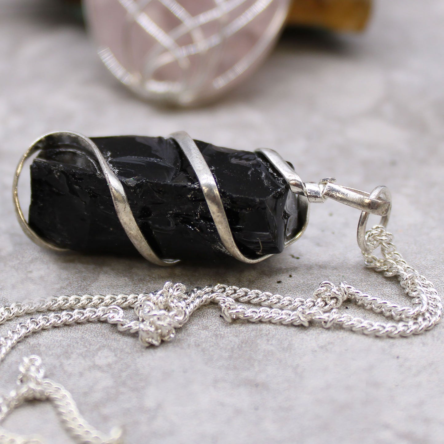 Cascade Wrapped Gemstone Necklace - Rough Black Onyx on a gray surface