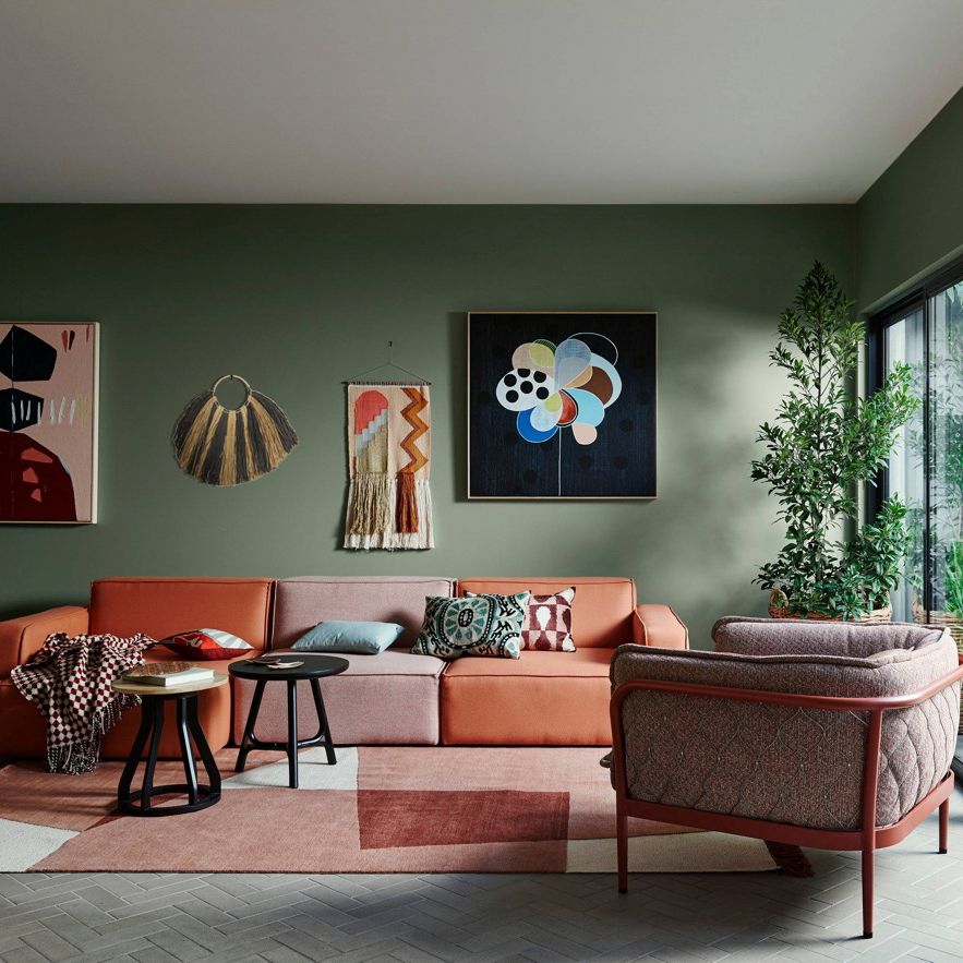Modern living room with a pink sectional sofa, abstract art on the wall, and a patterned rug.